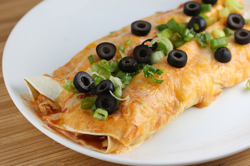 Rolled enchiladas covered in sauce with green onions