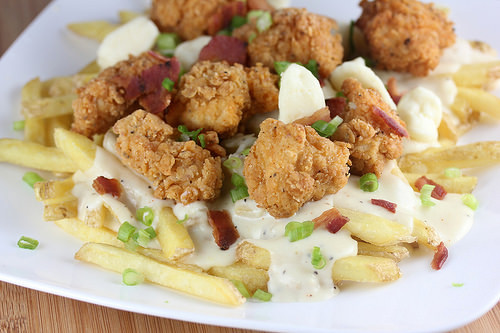 Close-up of fried chicken poutine with crispy chicken, cheese curds, and bacon on fries
