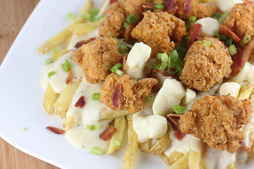 Fried chicken poutine with fries, cheese curds, gravy, chicken, bacon, and green onions