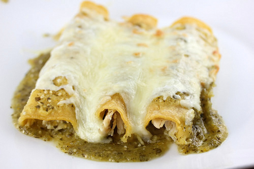 Green chicken enchiladas topped with cheese and sauce