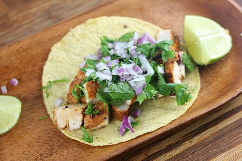 Grilled chicken street taco with onions, cilantro, and lime wedges