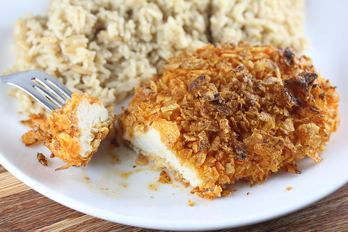 Fork cutting into kettle chip crusted chicken with rice