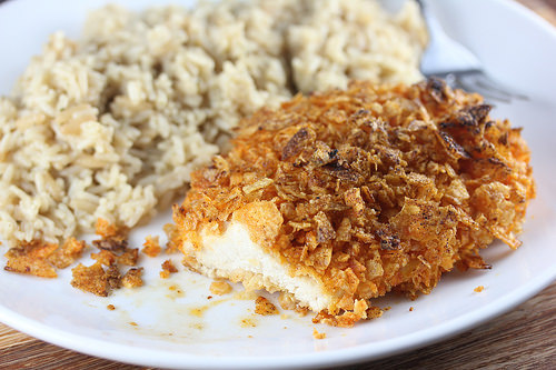 Kettle chip crusted chicken with rice on a white plate