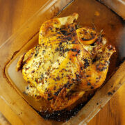 Lemon and rosemary roasted whole chicken in a glass baking dish