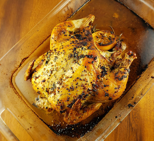 Lemon and rosemary roasted whole chicken in a glass baking dish