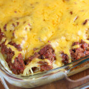 Baked spaghetti casserole topped with melted cheddar cheese