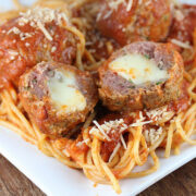 Mozzarella stuffed meatballs served over spaghetti with marinara