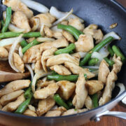Stir-fried chicken with green beans and onions in a skillet