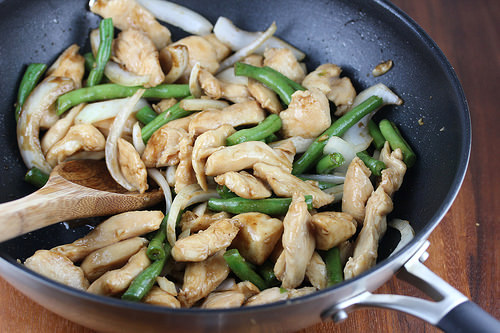 Stir-fried chicken with green beans and onions in a skillet