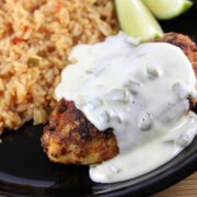 Close-up of the plated chicken topped with creamy queso beside rice