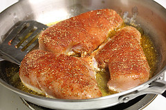 Seasoned chicken breasts searing in a skillet