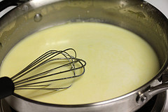 A saucepan of smooth, creamy white queso being whisked