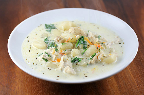 Bowl of creamy chicken gnocchi soup on a wooden table