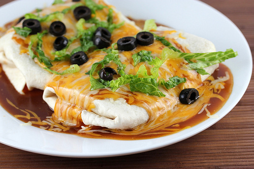Chicken wet burritos topped with cheese and olives
