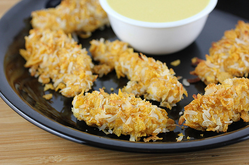 Crispy coconut chicken tenders on black plate