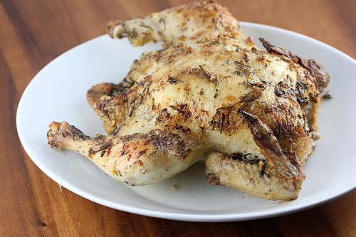 Whole roasted chicken with herb-seasoned skin on a plate