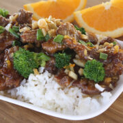 Close-up of orange beef with broccoli and citrus garnish