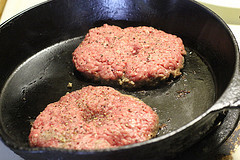 Beef patties searing in a cast iron pan