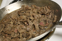 Cooked beef browning in a pan