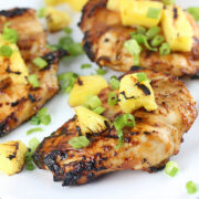 Grilled chicken with charred pineapple pieces on a white plate