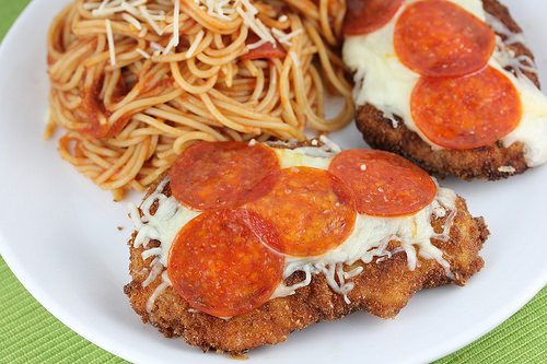 Breaded pizza chicken with pepperoni and cheese on a white plate