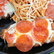Pizza chicken topped with melted cheese and pepperoni served with spaghetti