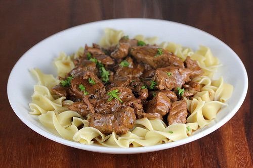 Plate of egg noodles topped with slow-cooked beef tips in brown gravy