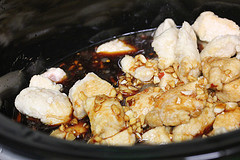 Raw chicken with sauce and cashews in slow cooker