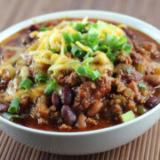 Bowl of slow cooker chili topped with cheese and green onions