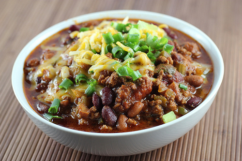 Bowl of slow cooker chili topped with cheese and green onions