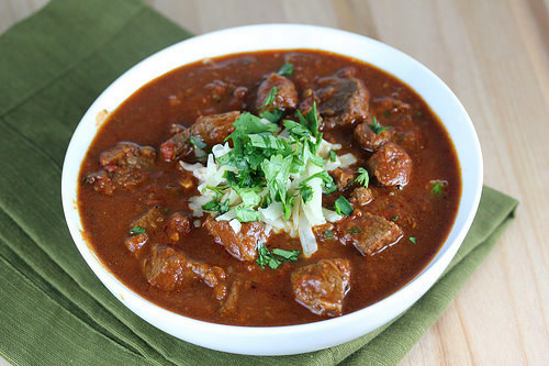 Slow cooker steak chili topped with shredded cheese and fresh herbs