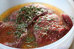 Raw marinated steak with herbs in bowl