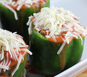 Unbaked stuffed green peppers topped with cheese
