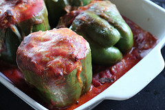 Stuffed green peppers in baking dish with sauce