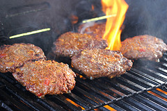 Burger patties cooking over open flame