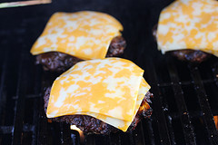 Cheeseburgers grilling with melted cheddar