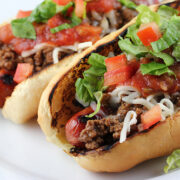 Taco dogs topped with lettuce tomato and cheese