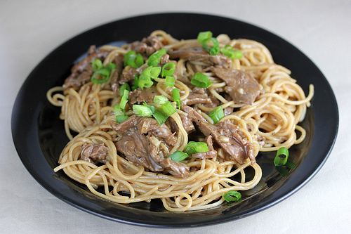 Teriyaki noodles topped with sliced beef and green onions