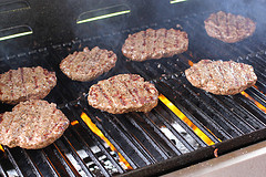 Burger patties grilling over open flame