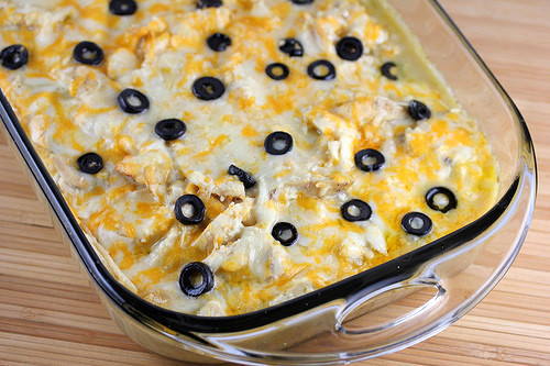 White chicken enchilada bake topped with cheese and black olives