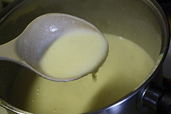 Creamy alfredo sauce in saucepan with ladle