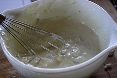 Creamy sauce mixed in white bowl with whisk