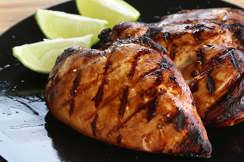 Close up grilled chicken with lime wedges