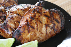 Two grilled chicken breasts on black plate