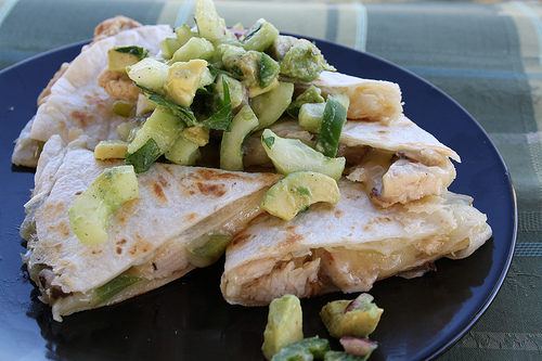 Sliced grilled chicken quesadillas topped with avocado salsa