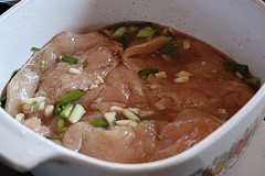 Raw chicken breasts marinating with garlic and green onions