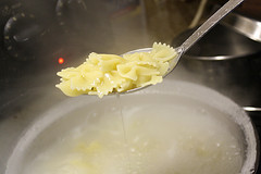 Cooked bowtie pasta draining from spoon