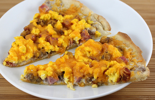 Breakfast pizza slices on white plate