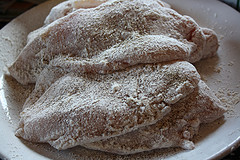 Raw chicken cutlets coated in flour