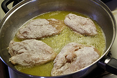 Floured chicken breasts frying in butter